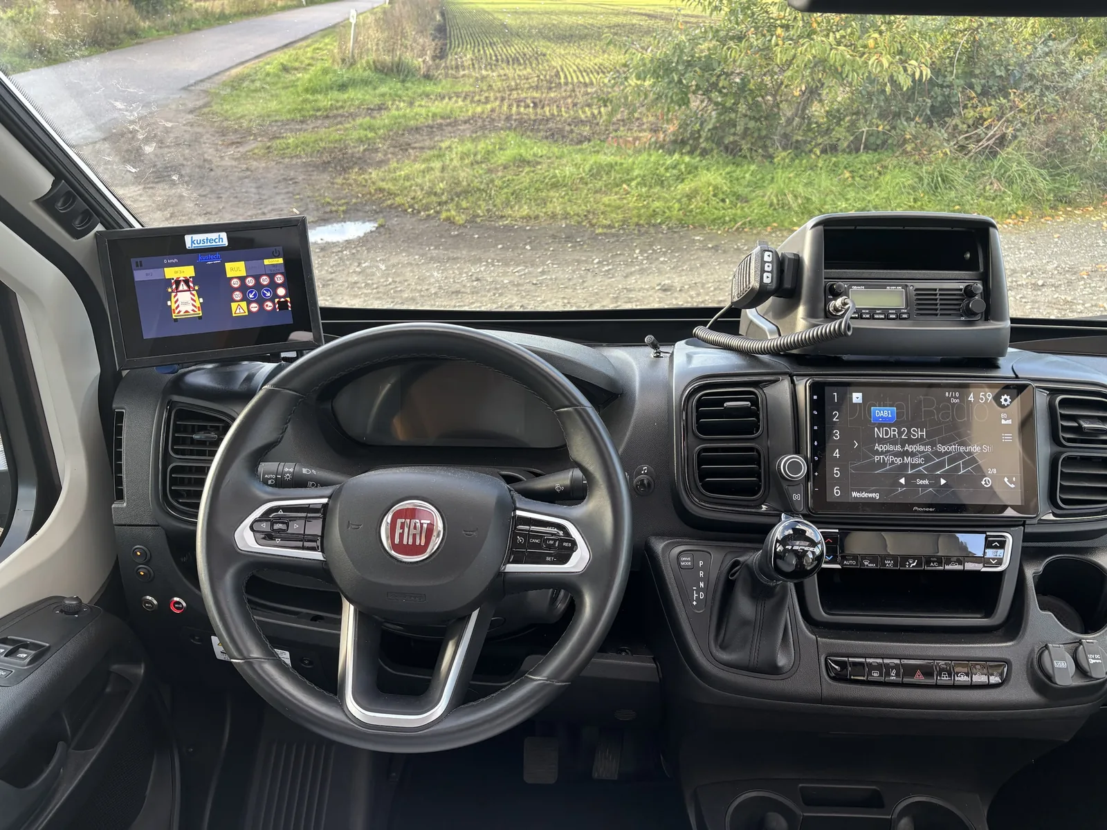 Cockpit eines Fiat Ducato mit Kustech-Bedieneinheit links und Funkgerät rechts